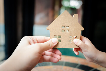 Baby Hands holding a house model with mother hand. The concept of relocation, mortgage, inheritance, family assurance protection and legacy planning. 