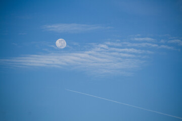 Fototapeta premium Full moon, over the blue sky, clouds and a jet