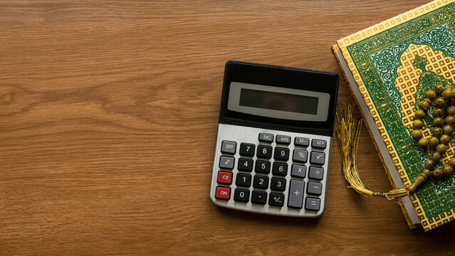 Islamic financing . Business and finance concept with calculator, Quran and rosary beads on wooden background.