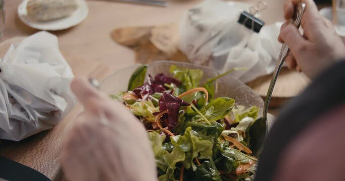 Mixing vegetable salad fork spoon female hands over shoulder close up