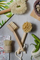 Bamboo wood brushes and natural bristles, with ecological accessories, friendly to the environment, on a light gray background, with colors such as green and some green or serrano peppers in a bag. 