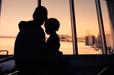 Fototapeta na wymiar Single mother and child sitting at airport. Refugee immigrant concept. 