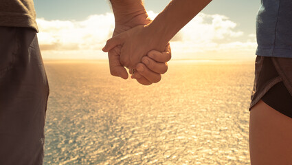 Couple flying hands facing ocean sunrise 
