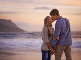 Every kiss feels like our first. Shot of a young couple enjoying a romantic kiss on the beach at sunset.