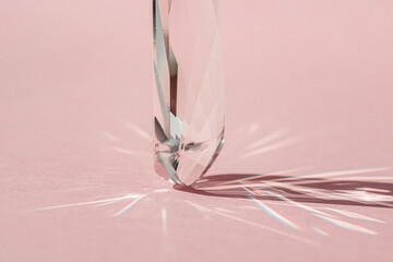 Crystal prism with light diffraction of spectrum colours and reflection with trendy light and hard shadows on pink background. Light spectrum reflected through glass prism. Banner