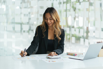 Portrait of businesswoman with laptop writes on a document at her office