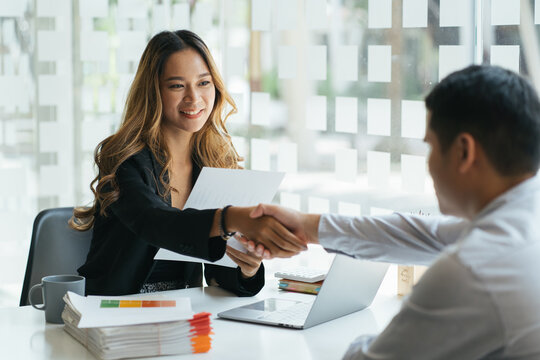 Pretty asian business woman shaking hands with businessman in her office during meeting