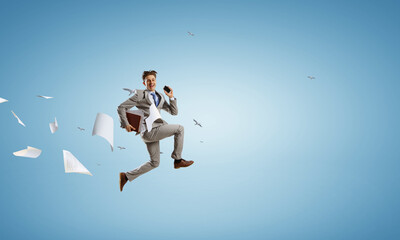 Fototapeta na wymiar Portrait of energetic businessman jumping in open air . Mixed media