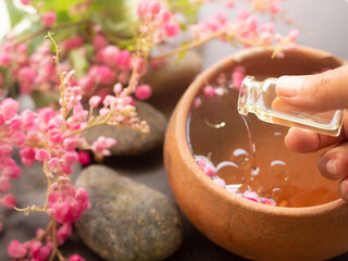 Hand woman pour coconut oil in to aroma essential smell rose flowers with zen pebbles.massage...