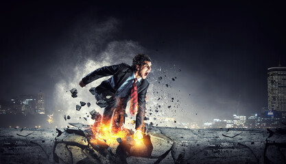 Determined businessman leaving fire trails on asphalt . Mixed media