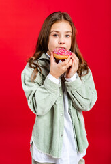 portrait of a beautiful girl in a green denim jacket and white shirt with loose hair. teenager with donut. on a red background