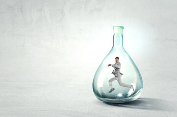 Young businessman dancing inside glass bottle . Mixed media