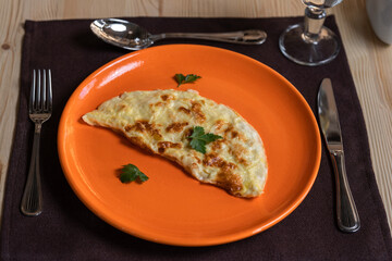 A photo of an omelette is laid out on an orange plate.