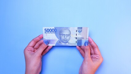 Indonesian Rupiah the official currency of Indonesia. woman's hand is making a payment. Female hand...