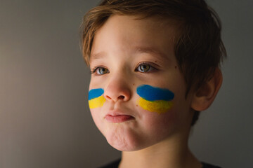 Portrait of a Ukrainian boy with a face painted with the colors of the Ukrainian flag. Ukrainian...