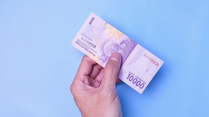 Indonesian Rupiah the official currency of Indonesia. Man's hand is making a payment. Business Loan Income Money Investment Economy and Finance Concept Uang 10000 10.000 Rupiah. Prosperity Concept.