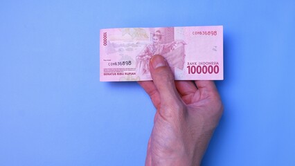 Indonesian Rupiah the official currency of Indonesia. Man's hand is making a payment. Business Loan Income Money Investment Economy and Finance Concept Uang 100000 100.000 Rupiah. Prosperity Concept.