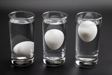 Eggs in water test on transparent glass , Egg freshness test on black background , Bad egg floats...