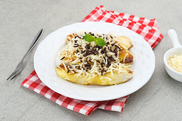 Pisang panggang, Grilled banana topped with chocolate sprinkles, grated cheese, and sweet white milk. Served on plate with mint leaves on grey background.
