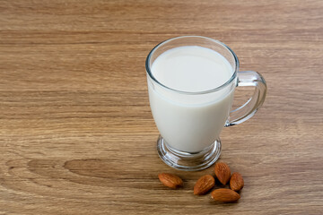 Almond milk in glass with almonds on the table. Space for text

