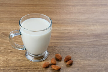 Almond milk in glass with almonds on the table. Space for text
