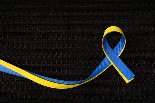 Blue and yellow ribbon for Ukraine on black grill cloth texture