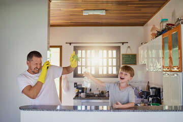Doing chores isnt as boring as it sounds. Shot of a father and his little son having fun while doing chores together at home.