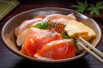 Japanese donburi rice bowl with caviar, salmon meat, scrambled eggs and leaf on a plate,...