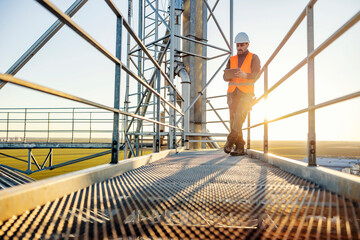 An industry worker scrolling on tablet while standing on height.