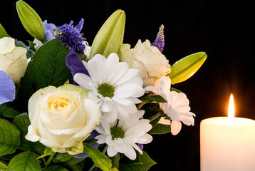 Funeral Bouquet purple White flowers and burning white candle, Sympathy and Condolence Concept on...