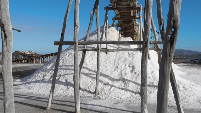 Industrial extraction of table salt on the Dominican coast. Mountains of sadochnaya oli to dry in the open air. Wooden supports under the railroad. Sunny day on a tropical peninsula.