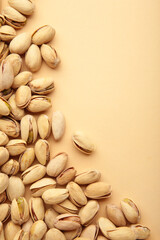 Pile of Pistachios on the beige background. Vertical photo.
