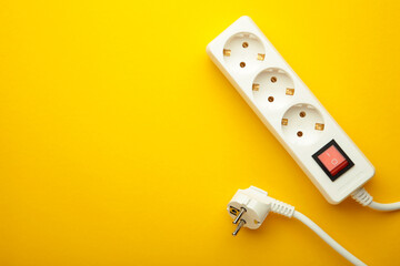 Electric white portable socket on yellow background