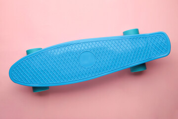 Penny Skate board blue with blue wheels on pink background.