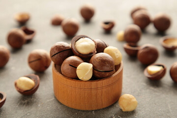 Macadamia nuts on wooden bowl on grey background. Top view.