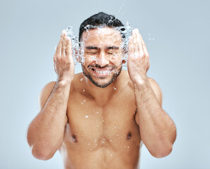 A guy who loves grooming. Studio shot of a handsome young man washing his face against a grey...