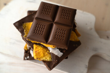 Raw Vegan Handmade Chocolate with dried mango fruits and coconuts slices close up. Chocolate bar with mango on a light background