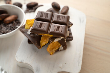 Raw Vegan Handmade Chocolate with dried mango fruits and coconuts slices close up. Chocolate bar with mango on a light background