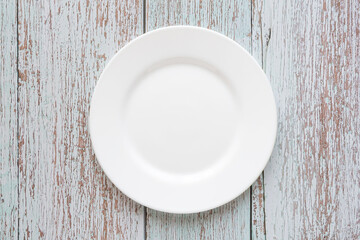 Plate on the background of a wooden tabletop. View from above. Small flat round white plate. Place for text.