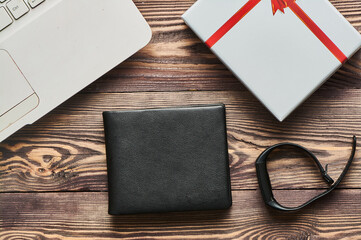 A black men's wallet lies on a wooden textured background