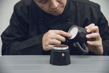 Asian barista is making hot coffee using moka pot