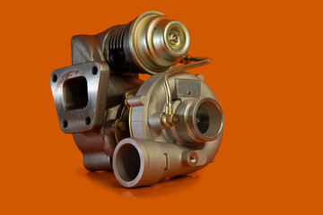 Brand new turbo charger or automotive turbine, vintage type or style, smaller turbo, isolated on orange background.