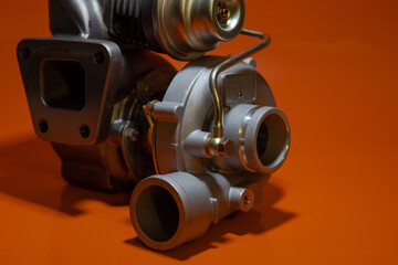 Brand new turbo charger or automotive turbine, vintage type or style, smaller turbo, isolated on orange background.