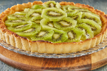 Ready-made kiwi pie, on wooden stand. French gourmet cuisine