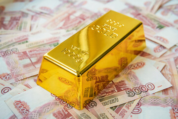 A kilogram gold bar is on the banknotes of 5000 rubles. Close up of banknotes with pure gold bar...