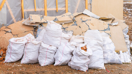 Dismantled facade. White bags with construction debris on the street