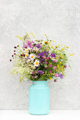 Bouquet of bright flowers in tin can vase on background grey stone wall. Template for postcard. Concept Women's day, Mothers Day, Hello summer or Hello spring