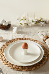 Fototapeta na wymiar Easter table setting in festive morning with organic egg, spring blossom flowers on linen tablecloth. Vertical format. Close up.