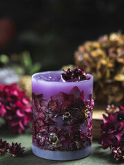 Handmade candles of a unique design, with different flowers, dry leaves on a light background....