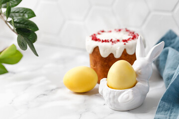 Easter eggs painted with turmeric in Yellow color in ceramic bunny. Traditional  easter cake with white glaze top. Greens